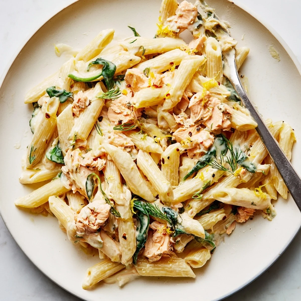 Creamy salmon penne pasta topped with flaky salmon pieces in a rich Parmesan lemon sauce
