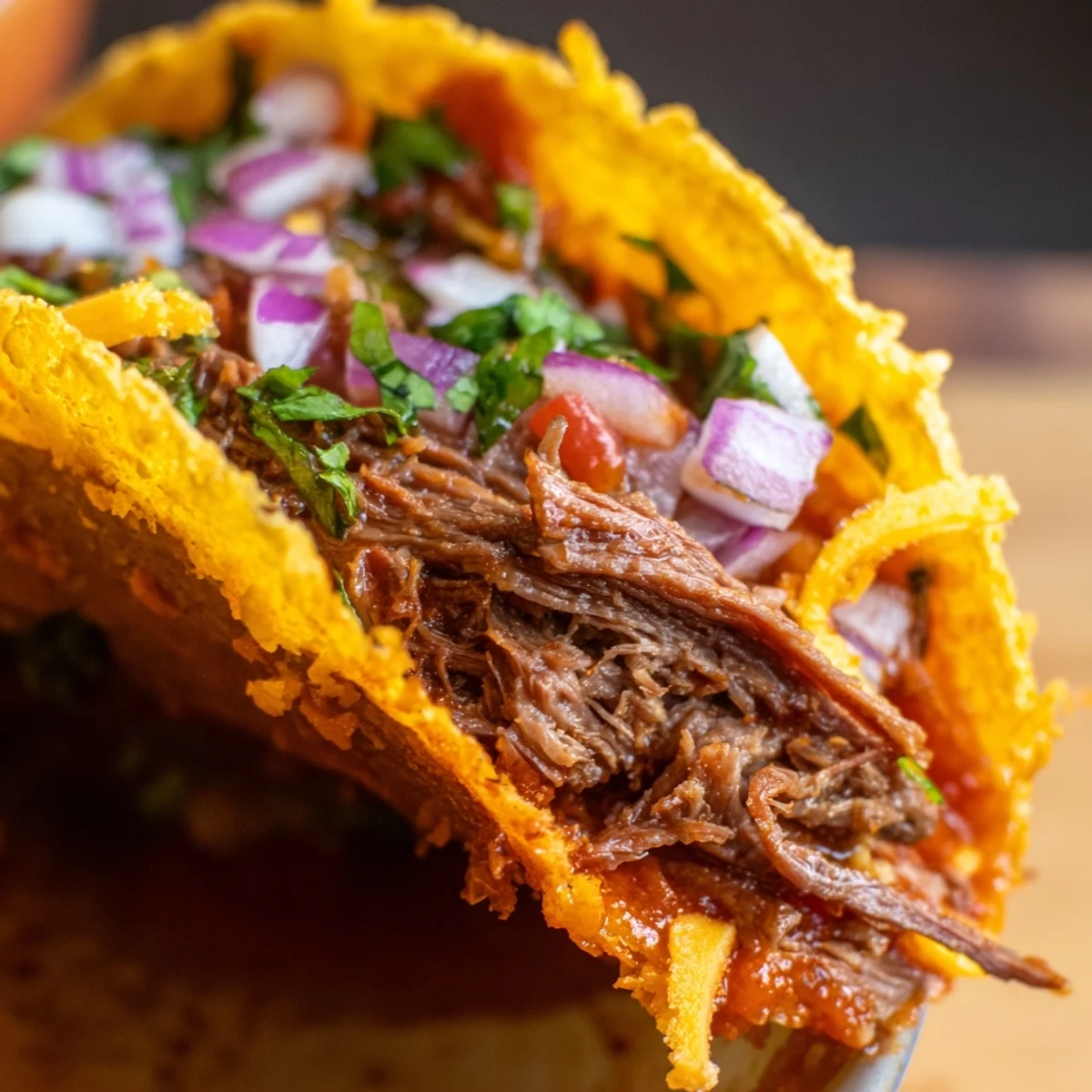 Golden shredded beef tacos with crispy melted cheese edges topped with fresh cilantro and red onion
