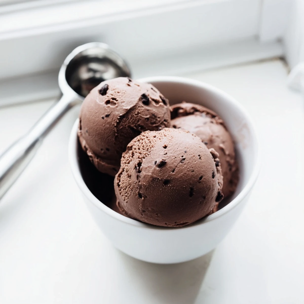 Homemade chocolate sourdough ice cream served in a vintage glass dish with fresh berries and sea salt garnish