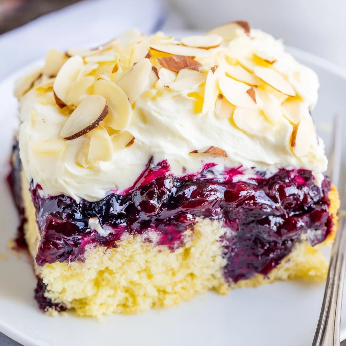 Freshly chilled Lemon Blueberry Poke Cake With Almond Topping garnished with toasted almond slices