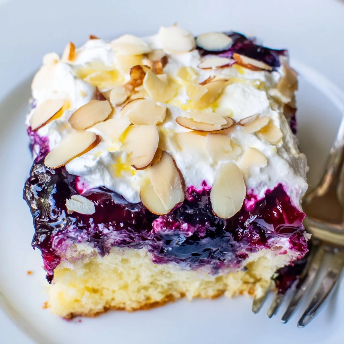 Slice of Lemon Blueberry Poke Cake With Almond Topping on plate, almond crunch