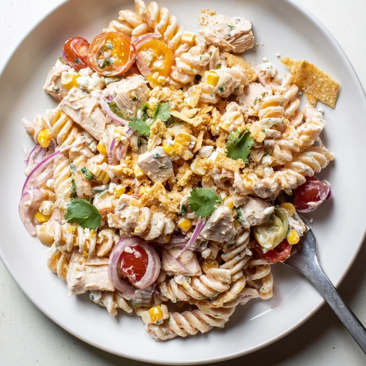 Creamy Mexican street corn chicken pasta salad topped with crunchy crushed tortilla chips and crumbled Cotija cheese