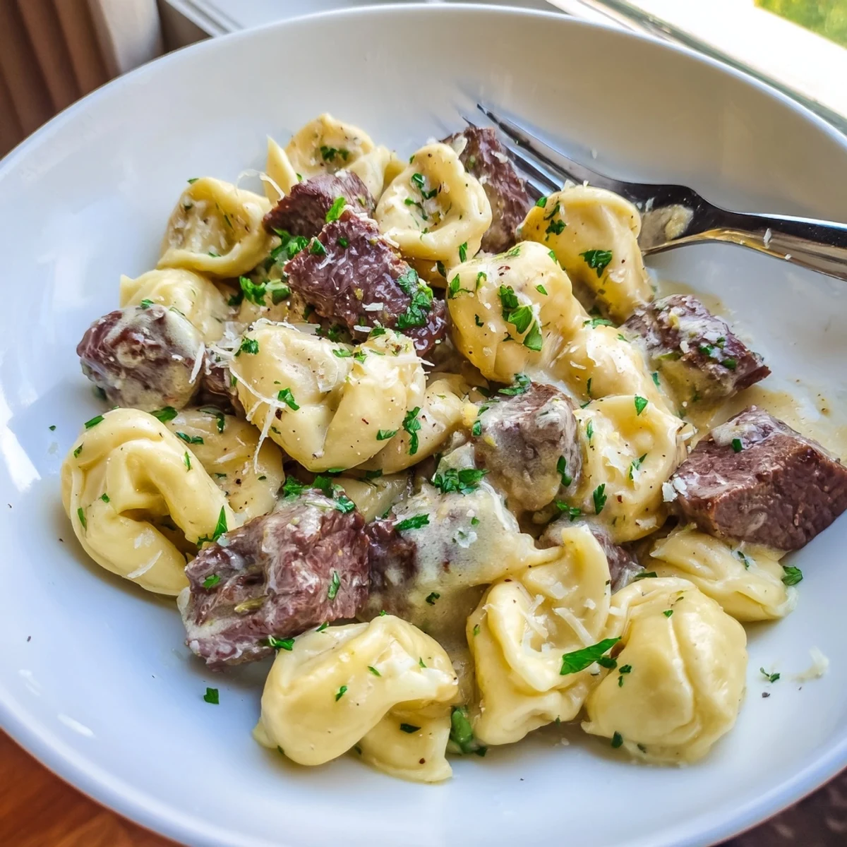 Steaming bowl of garlic steak tortellini with seared sirloin and silky garlic butter sauce