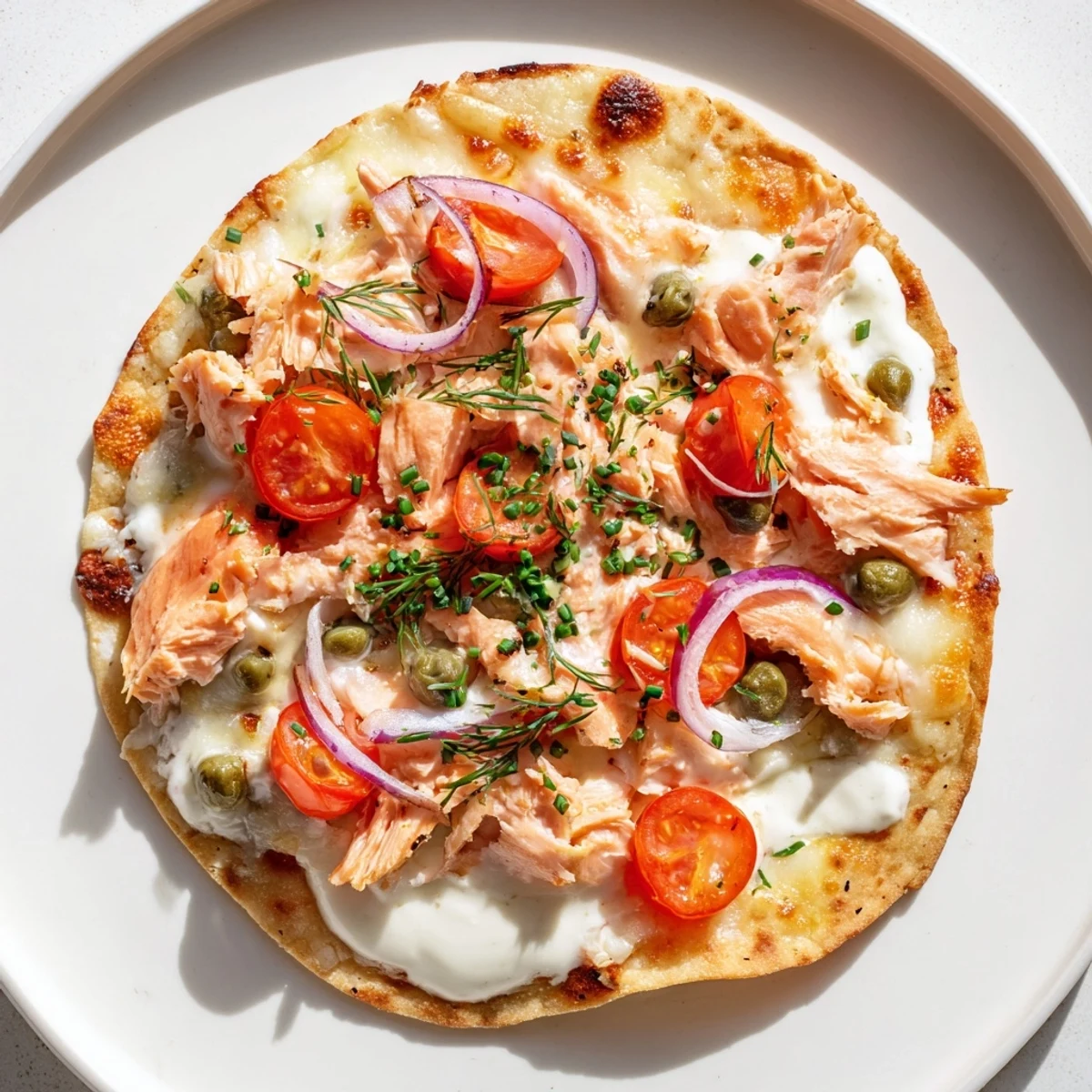 Vibrant salmon tortilla pizza topped with red onions, cherry tomatoes, and capers
