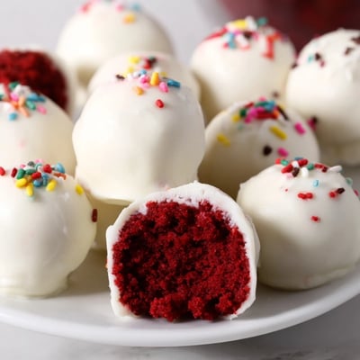 A close-up of red velvet cake pops with creamy white chocolate glaze, perfect for gifting or celebrations.