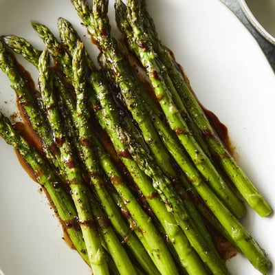 Close-up of roasted asparagus with balsamic glaze, showing caramelized tips and glossy drizzle. 