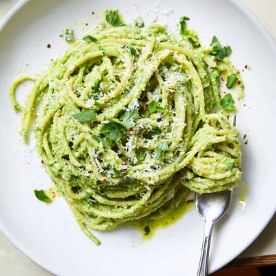 Vibrant green goddess pasta sauce served in a bowl with Parmesan garnish